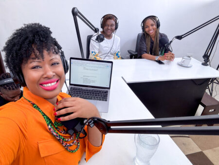 Three women sit in front of microphones for a podcast discussion
