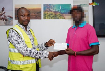 Sulaiman Kamara, first big money winner for offline football bets, holding a cheque from Mercury International