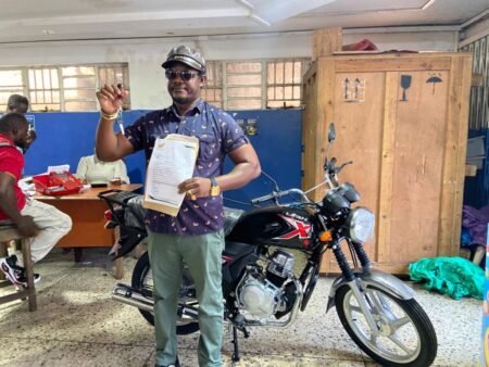 Joseph Gando, Winner of the Grand Prize, Posing In Front of His Brand New Motorbike
