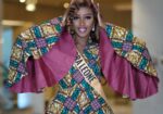 Sierra Leone contestant in an African wax-print outfit with wide cape sleeves and a Sierra Leone sash