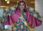Sierra Leone contestant in an African wax-print outfit with wide cape sleeves and a Sierra Leone sash